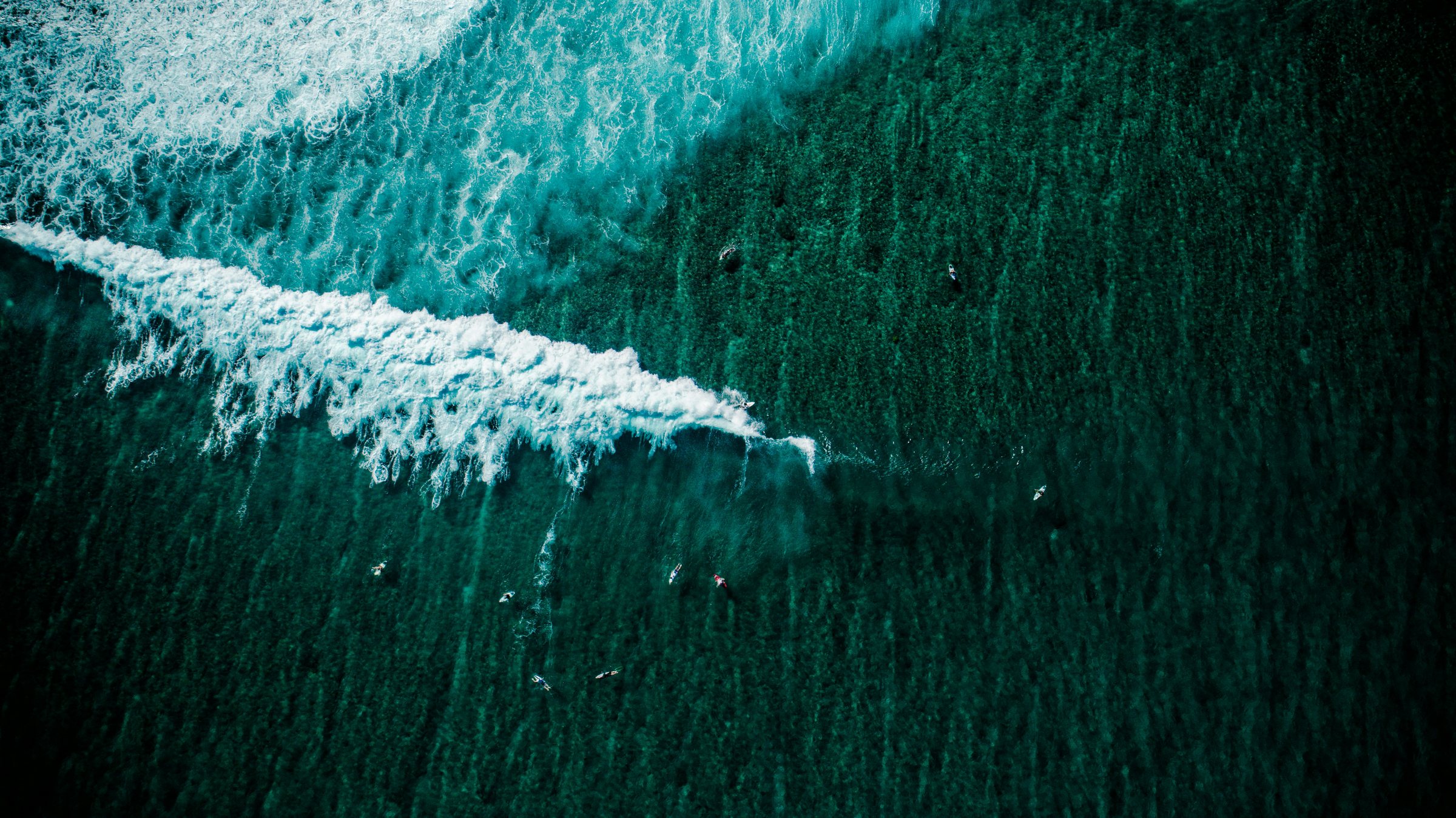 Aerial view of surfers riding and paddling out at the Cokes surf break